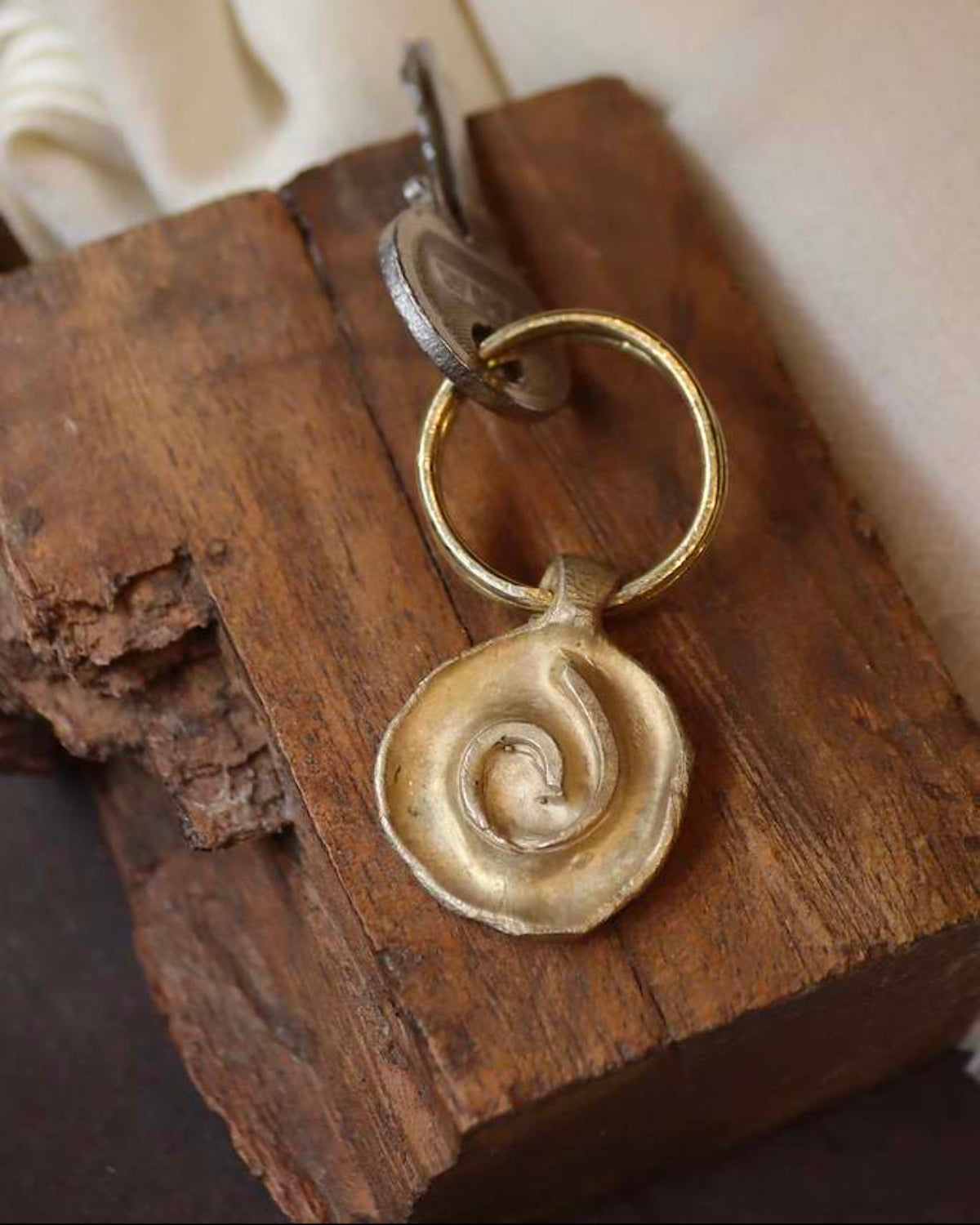 Llavero rústico con imagen de una espiral en latón. Hecho artesanalmente en España por Sandra Bellew.