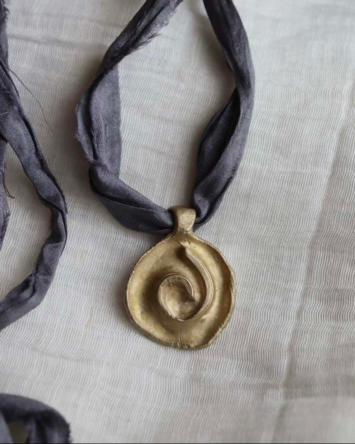 Colgante rústico de espiral celta en latón. Hecho artesanalmente en España por Sandra Bellew.