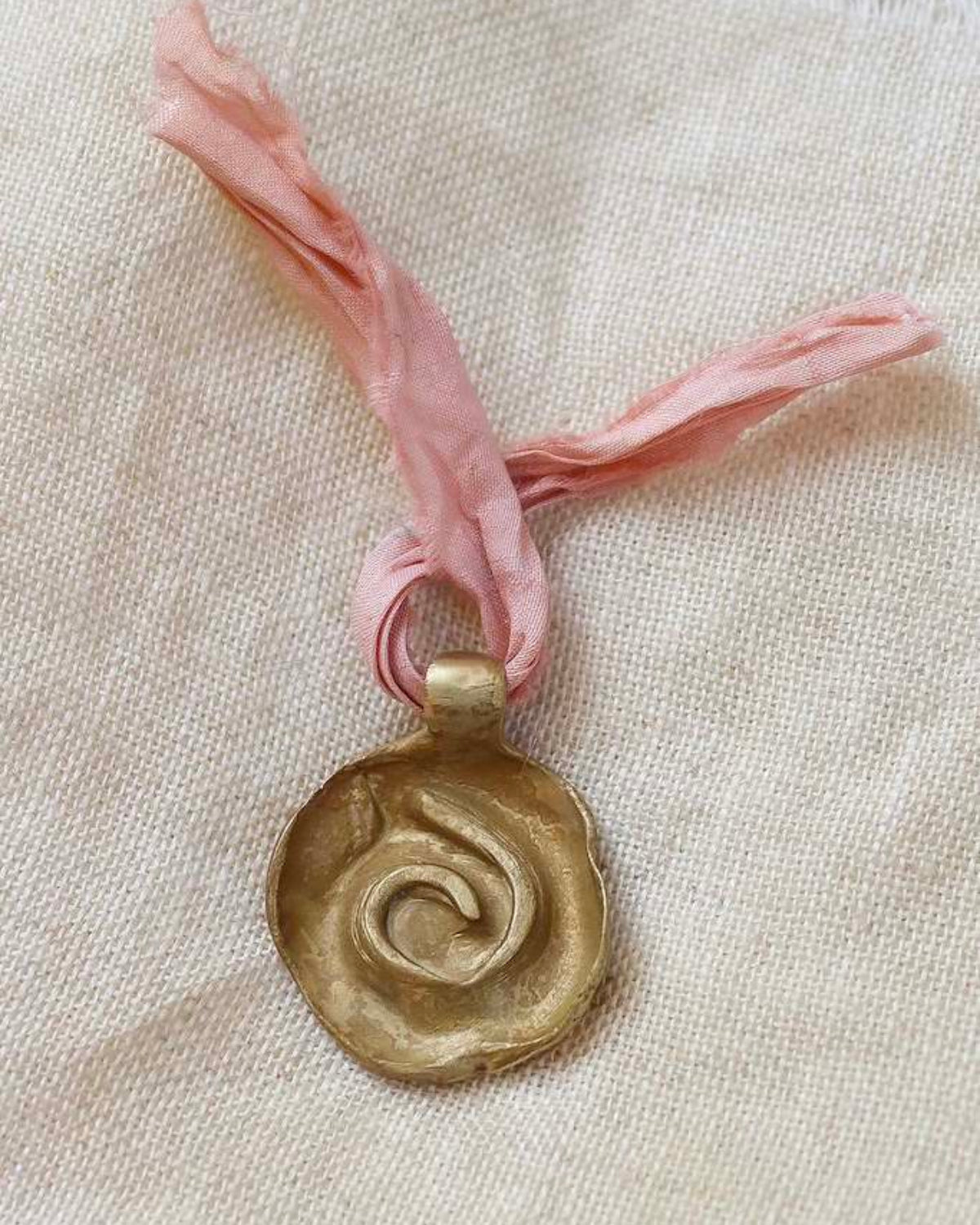 Colgante rústico de espiral celta en latón. Hecho artesanalmente en España por Sandra Bellew.