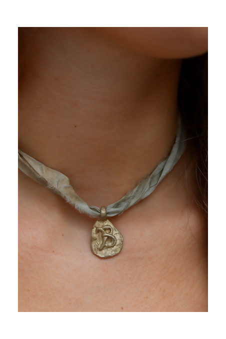 Colgante rústico con inicial en latón. Hecho artesanalmente en España por Sandra Bellew.