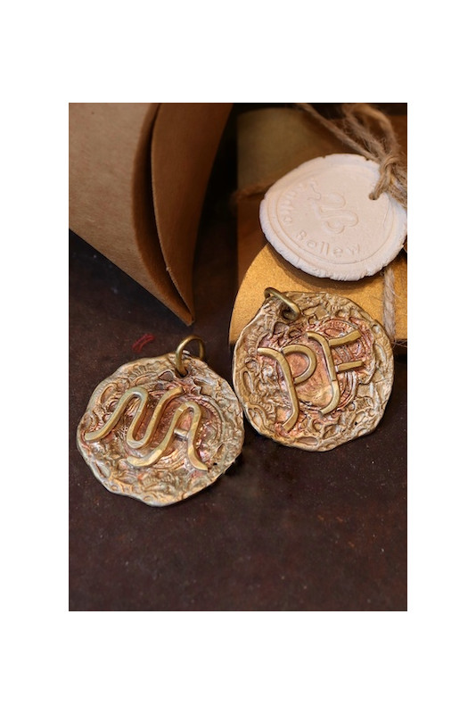Colgante rústico con dos iniciales en latón. Hecho artesanalmente en España por Sandra Bellew.