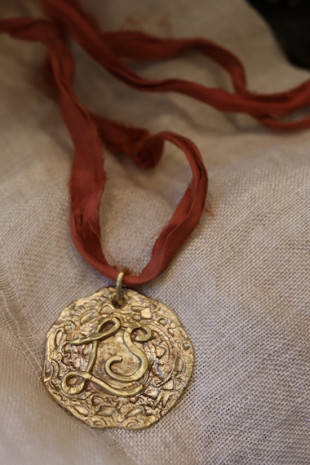 Colgante rústico con dos iniciales en latón. Hecho artesanalmente en España por Sandra Bellew.