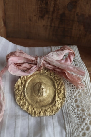 Medalla de cuna rústica de la Virgen de la Mercè en latón. Hecha artesanalmente en España por Sandra Bellew.