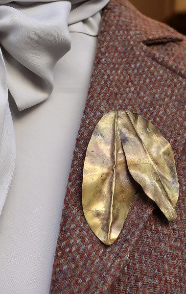 Broche con dos hojas en latón. Hecho artesanalmente por Sandra Bellew.
