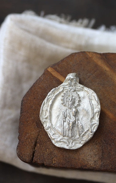 Medalla rústica de la Virgen del Puerto para carrito en plata. Hecha artesanalmente por Sandra Bellew.