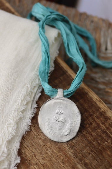 Medalla rústica del Sagrado Corazón en plata. Hecha artesanalmente por Sandra Bellew.