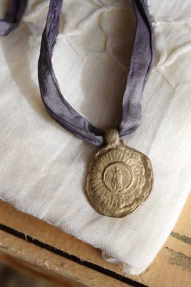 Medalla rústica de Santa Cristina en latón. Hecha artesanalmente en España por Sandra Bellew.