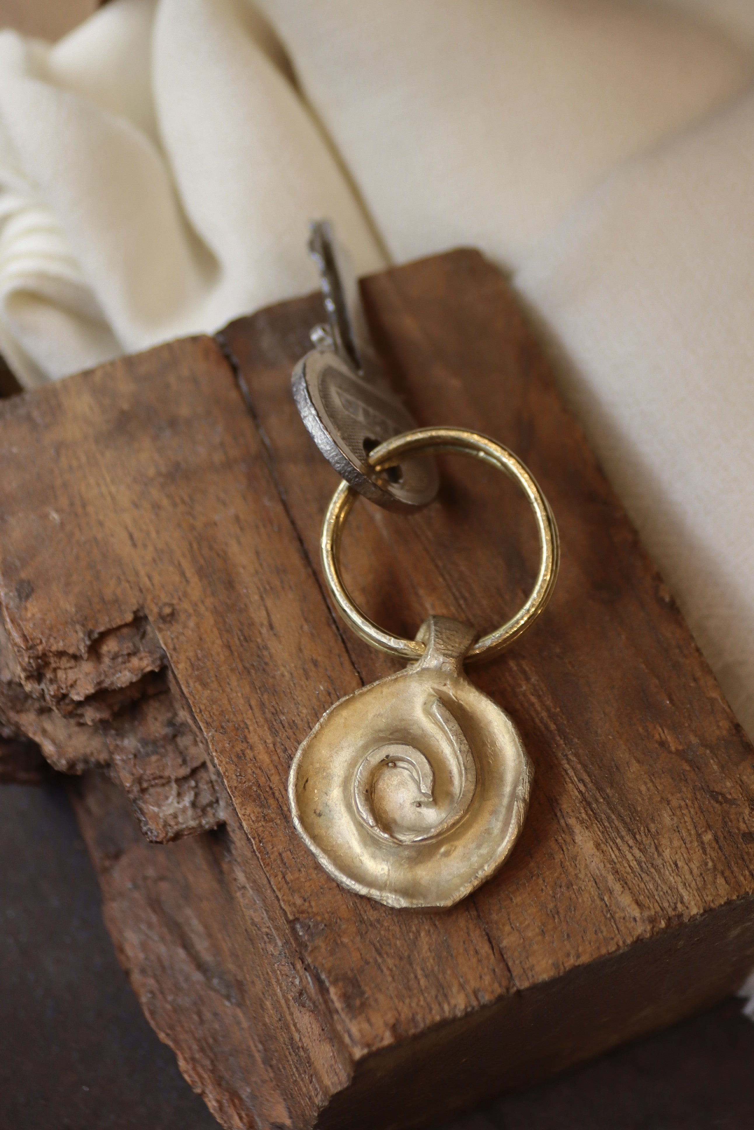 Llavero rústico con imagen de una espiral en latón. Hecho artesanalmente en España por Sandra Bellew.