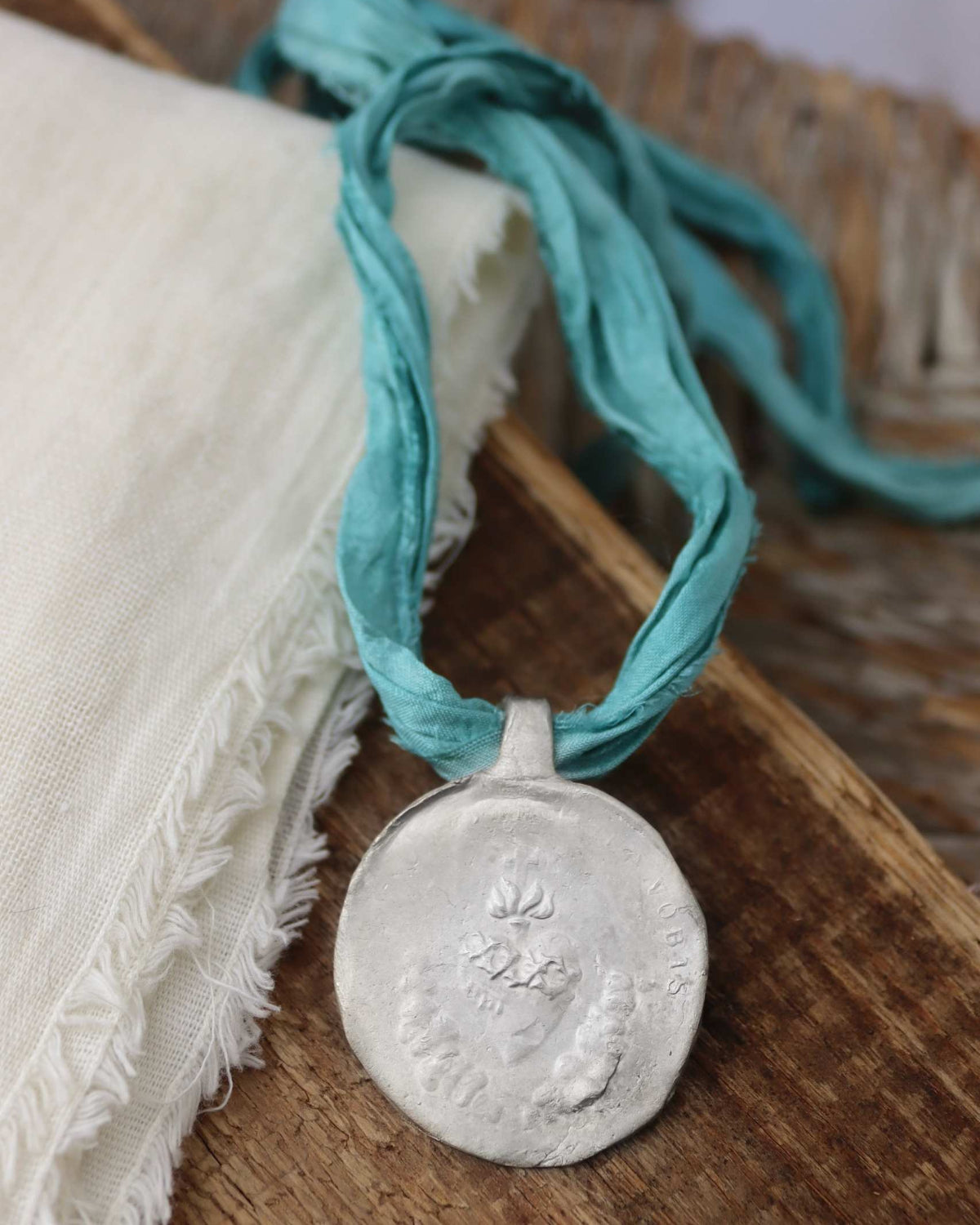 Medalla rústica del Sagrado Corazón en plata. Hecha artesanalmente por Sandra Bellew.